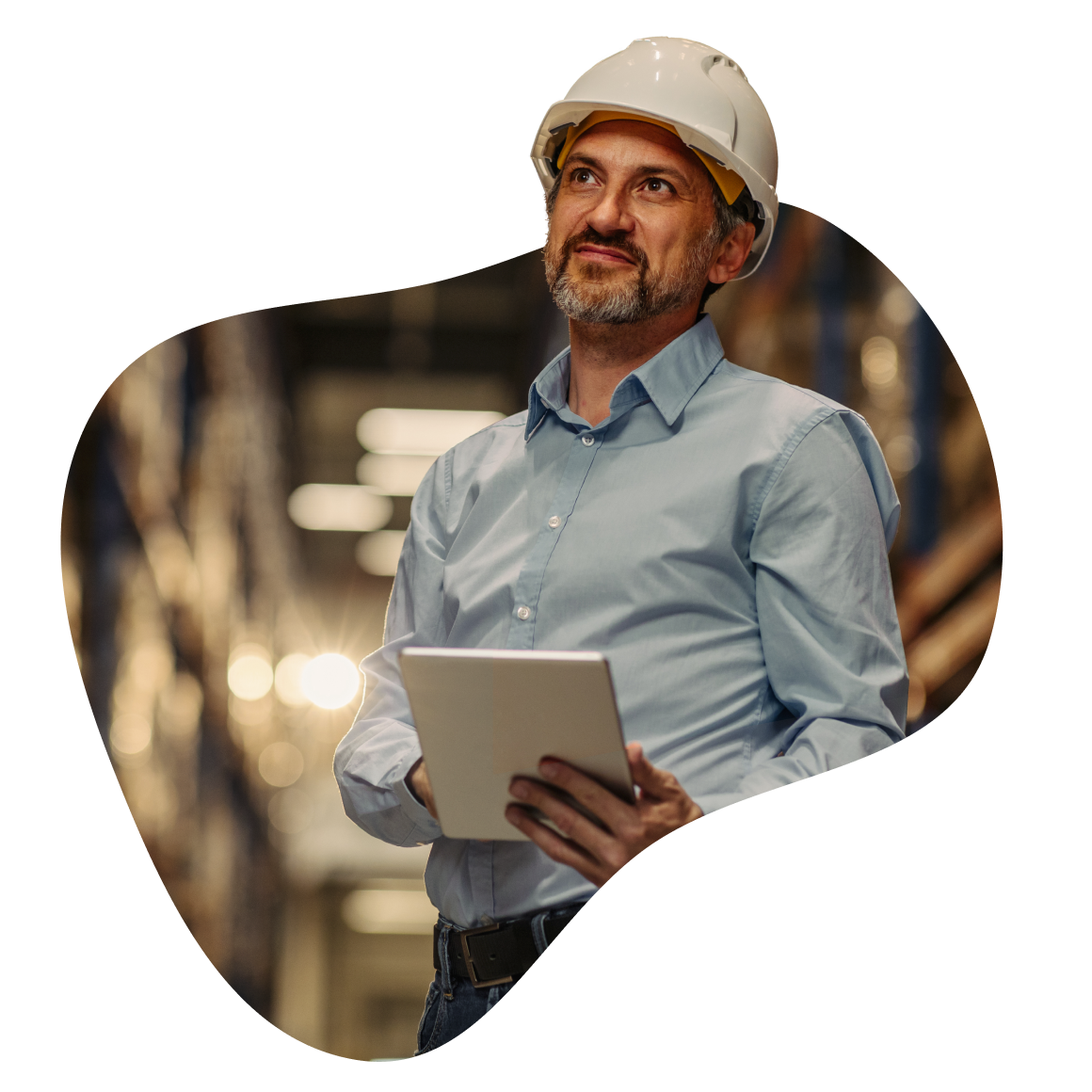 A man wearing a hard hat is holding a tablet, focused on his work in a construction or industrial setting